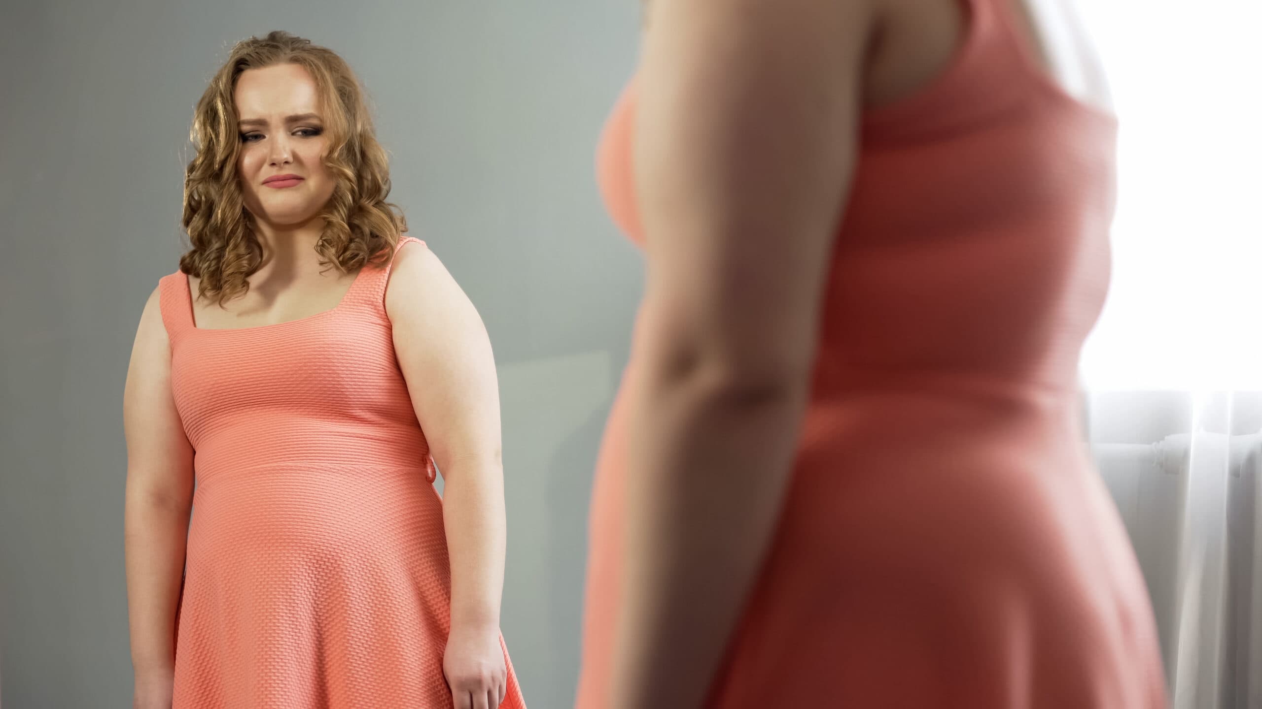 Young,female,looking,in,mirror,with,disgust,,ashamed,of,fat