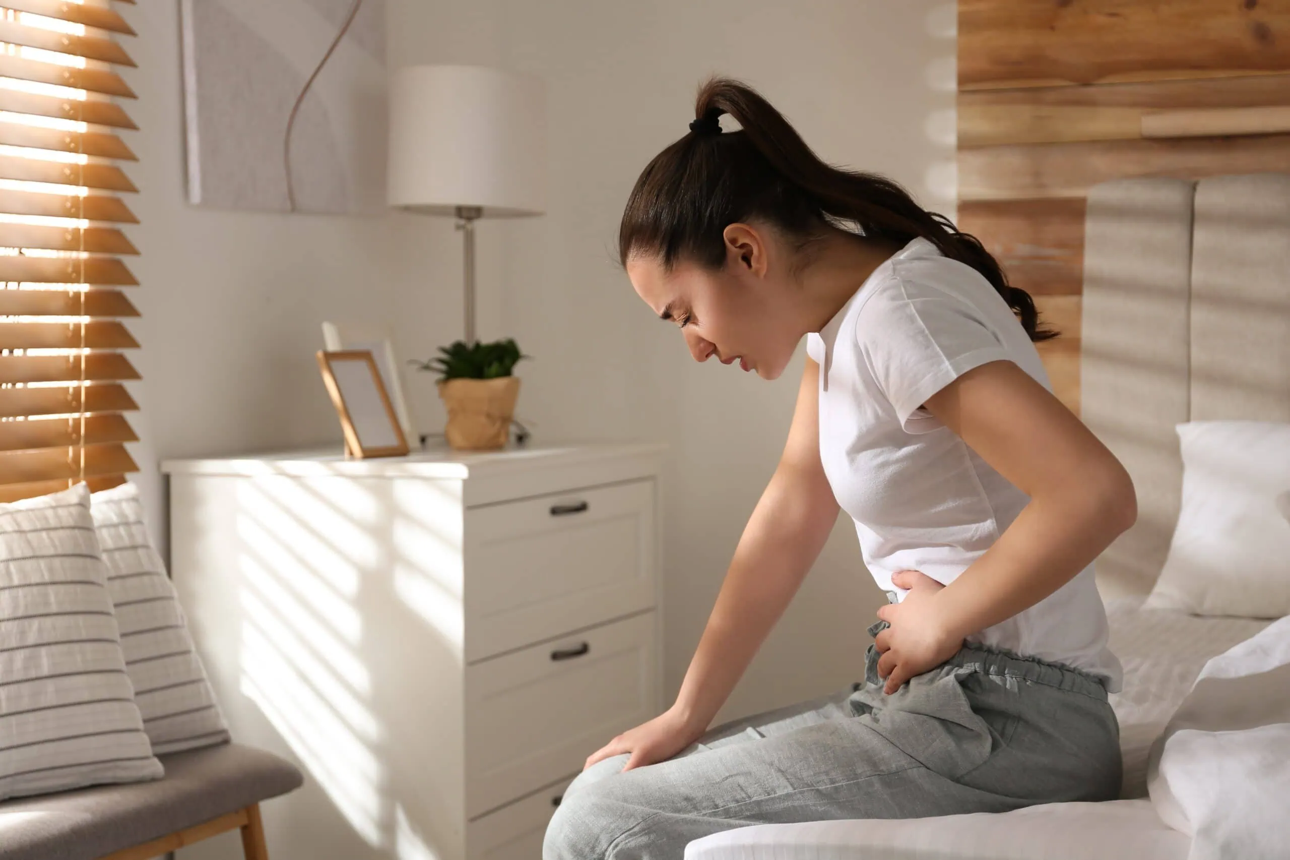 Young,woman,suffering,from,stomach,ache,on,bed,at,home,
